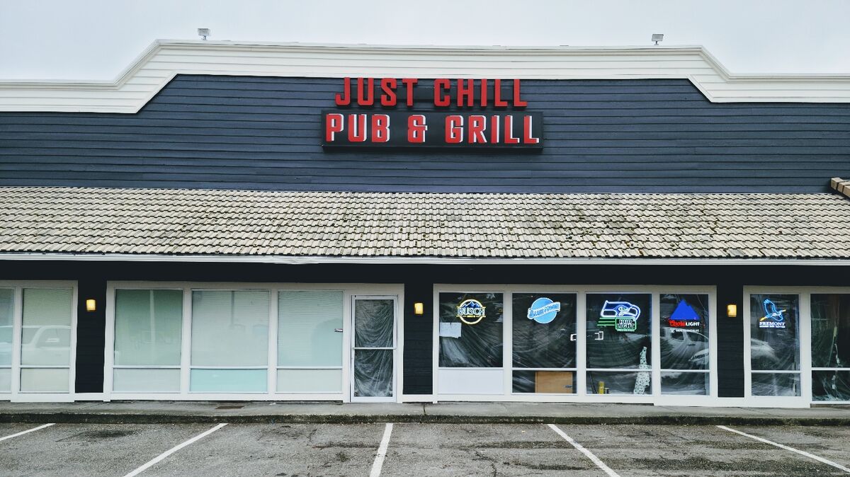 The Just Chill Pub & Grill storefront on Highway 99 in Lynnwood, red lettering on a dark navy façade with neon beer signs in the windows.